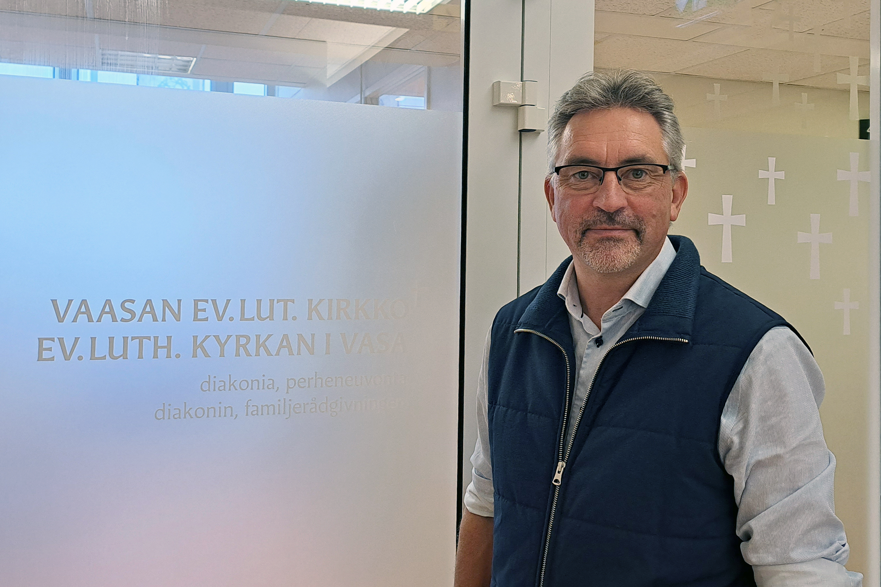 Mies lasioven edessä, jossa huurrettu teippas ja teksti Vaasan ev.-lut. kirkko, Ev.-luth. kyrkan i Vasa.