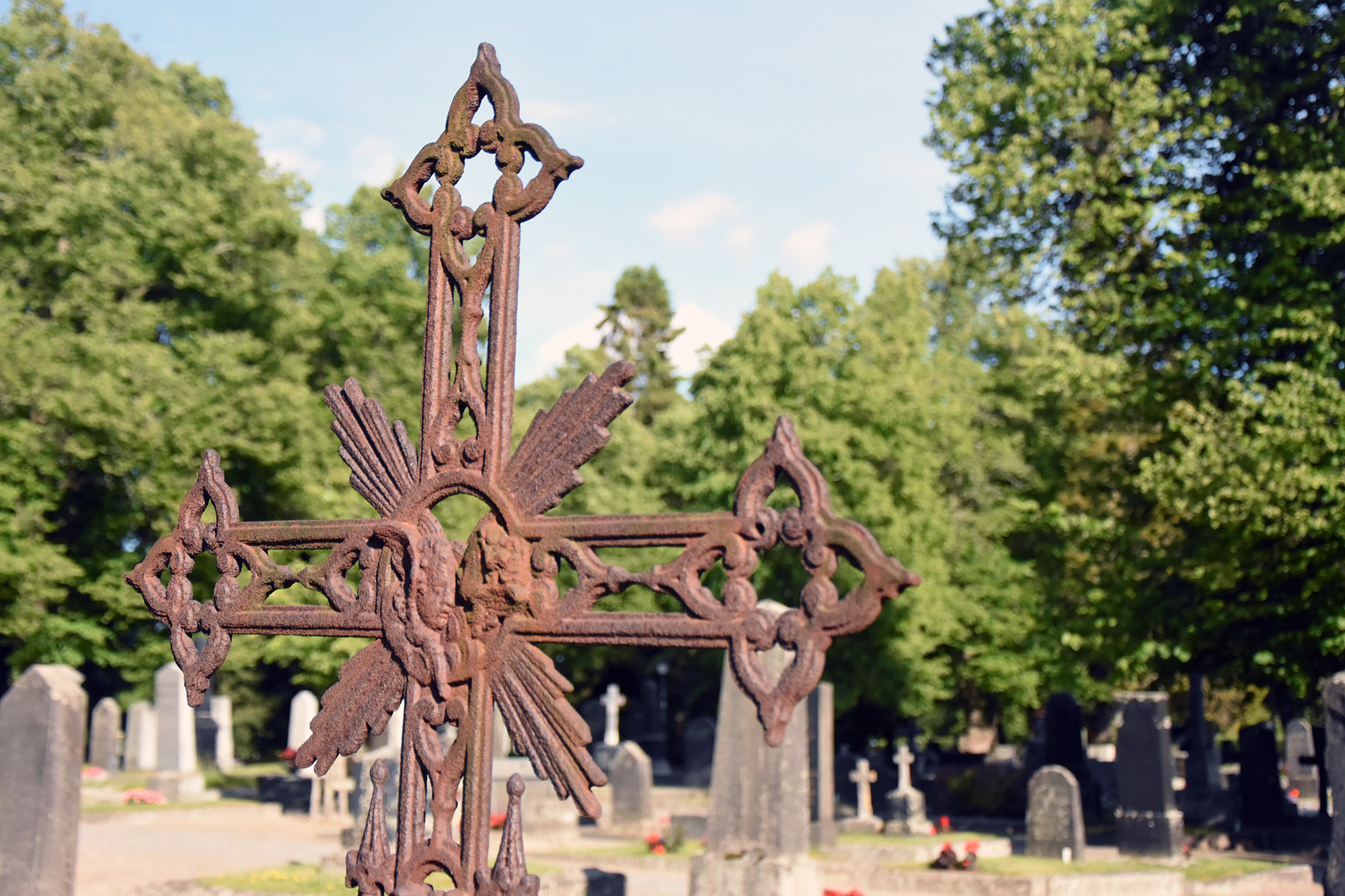 Ruostunut koristeellinen risti hautausmaalla.