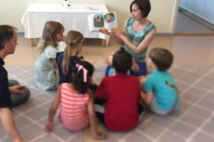 Kids sitting on the floor, listening to a Bible story.