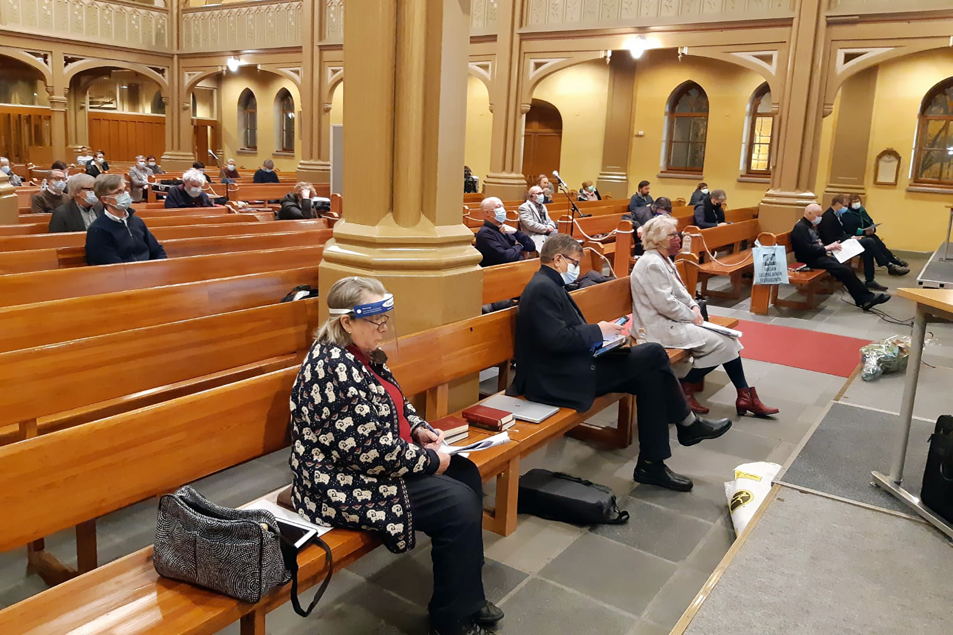 Ihmiset, joilla on kasvomaskit päällä, istuvat penkeissä Vaasan kirkossa.