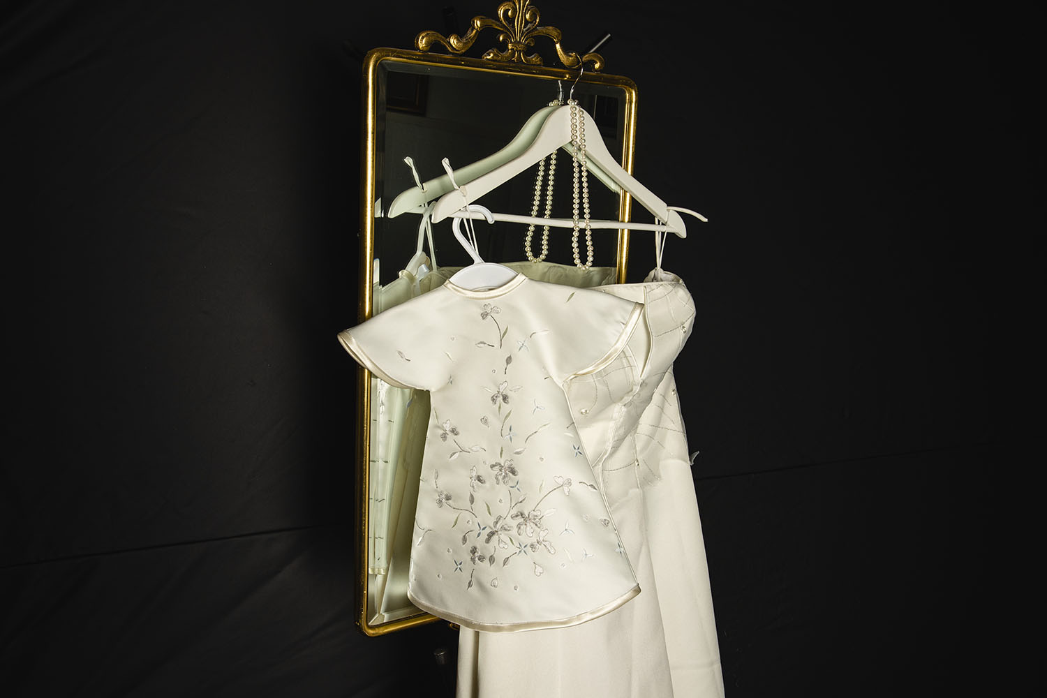 Pieni valkoinen mekko rikkinäisen morsiuspubvun päällä peilin päälle ripustettuina.