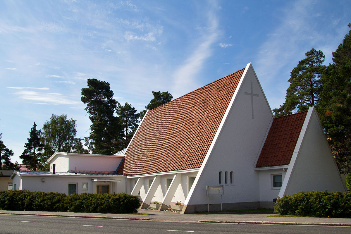 Kolmionmuotoinen valkoinen kirkko, jossa punainen tiilikatto