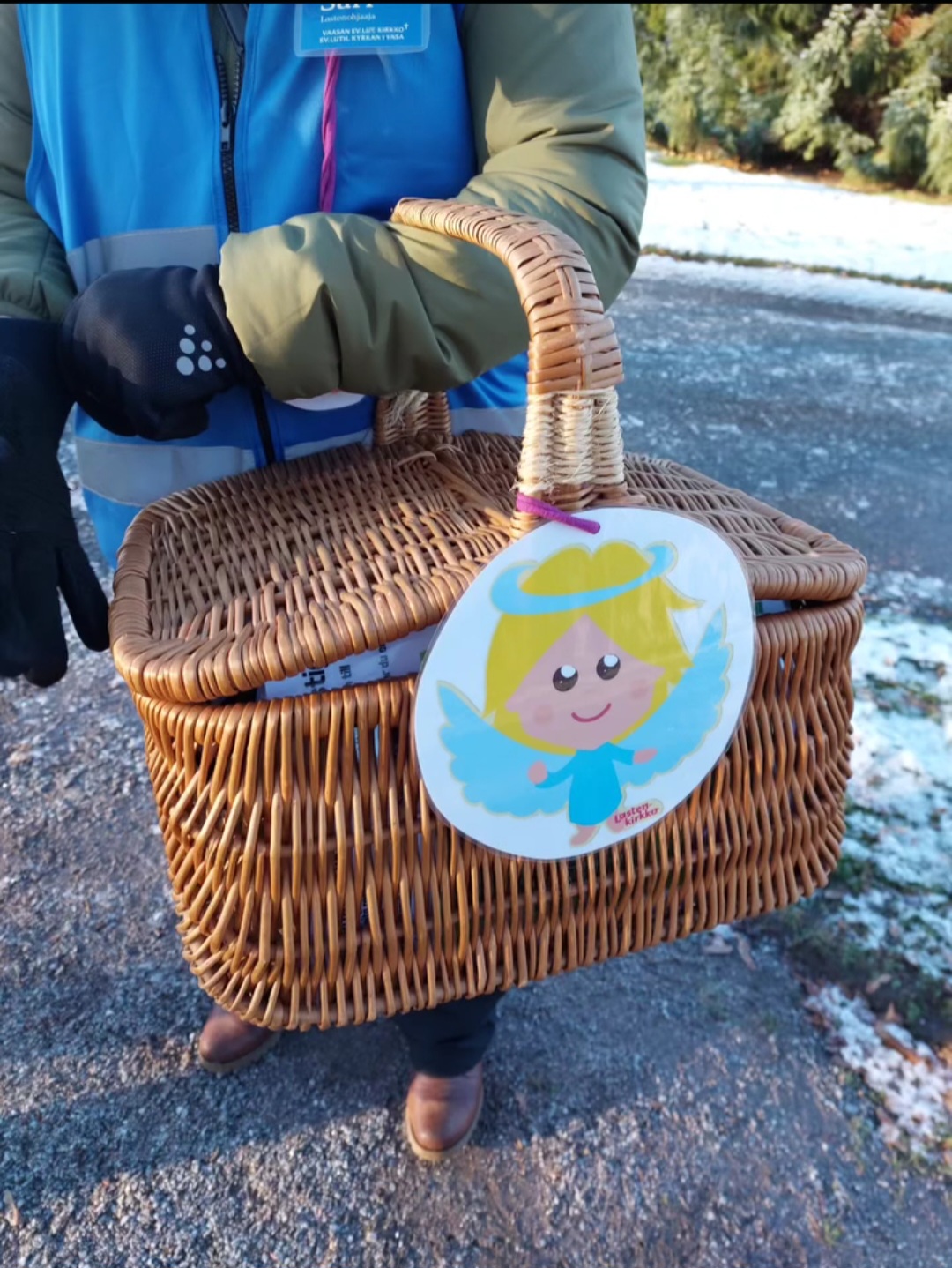 Ihminen pitää koria, jossa enkelin kuva.