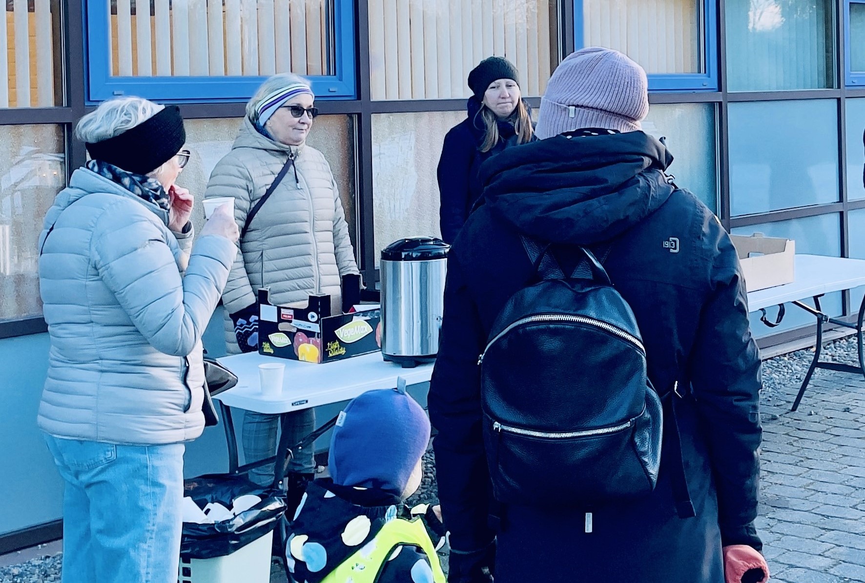 Ihmisiä tarjoilupöydän äärellä ulkona.
