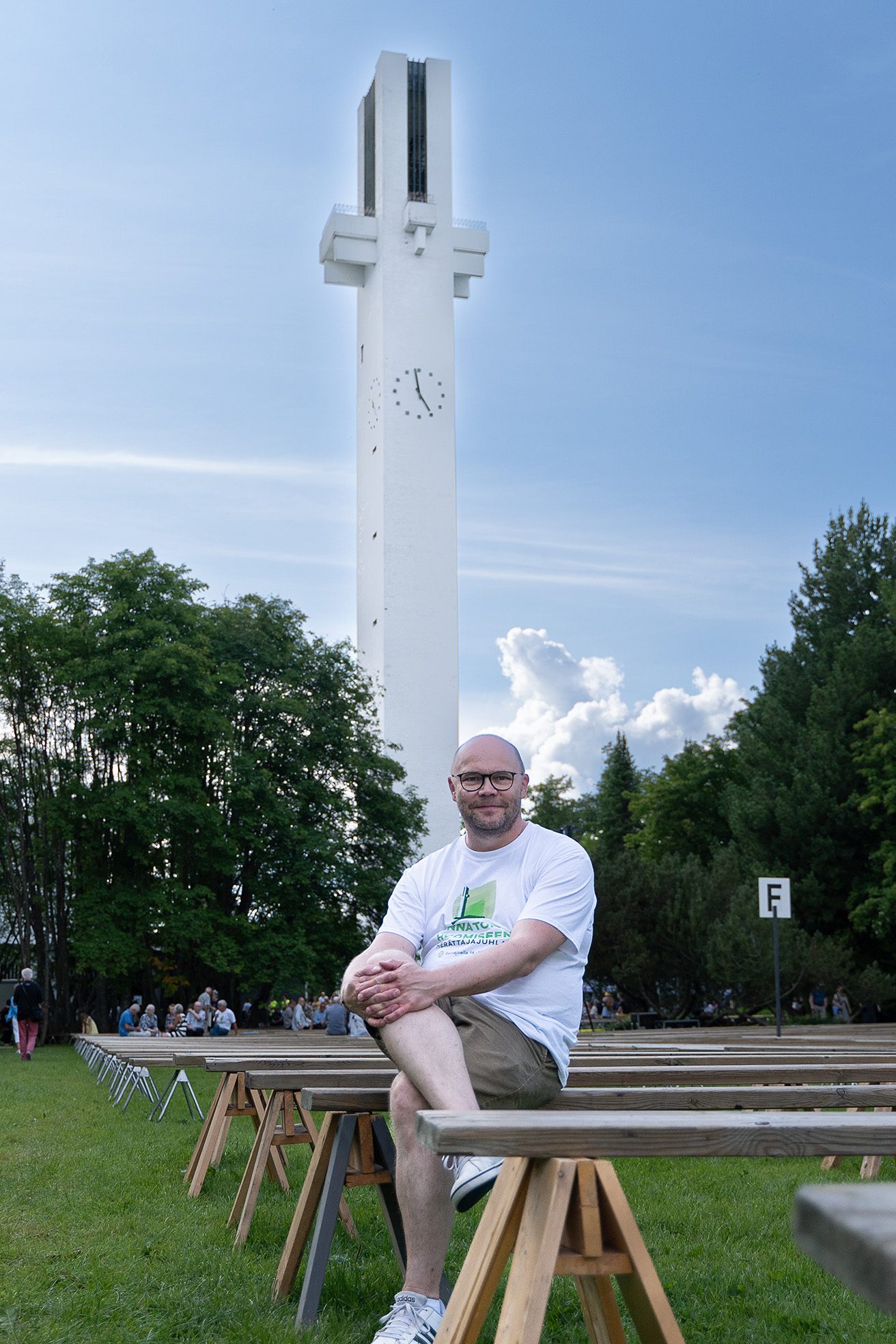 Mies istuu penkilä. Taustalla korkea kellotapuli.